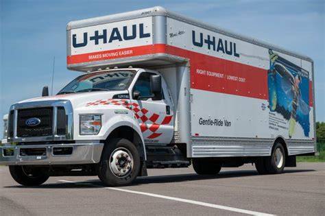 A variety of U-Haul trucks lined up in a rental facility.