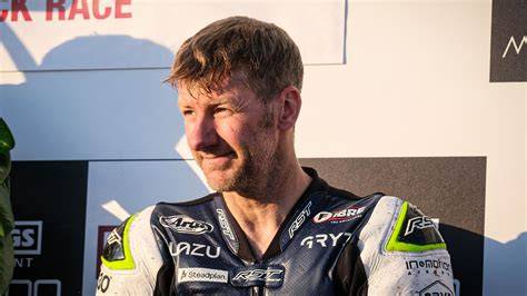 Ian Hutchinson is standing on the podium with a trophy after his race.