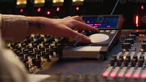 a music producer focused on fine-tuning faders during a recording session
