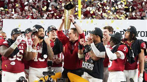 Indiana Hoosiers football coaches proudly displaying awards during a ceremony.