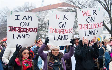A group of Indigenous activists holding signs in a demonstration for land rights