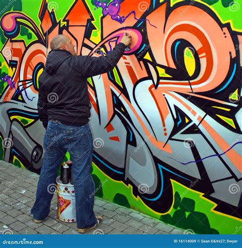 An artist demonstrating spray painting techniques on a wall.