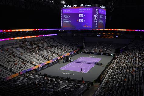 A well-maintained tennis court set up for a WTA 1000 tournament, complete with banners and seating.
